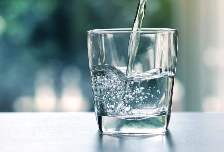 en närbild som fångar ögonblicket när friskt vatten hälls i ett mindre glas